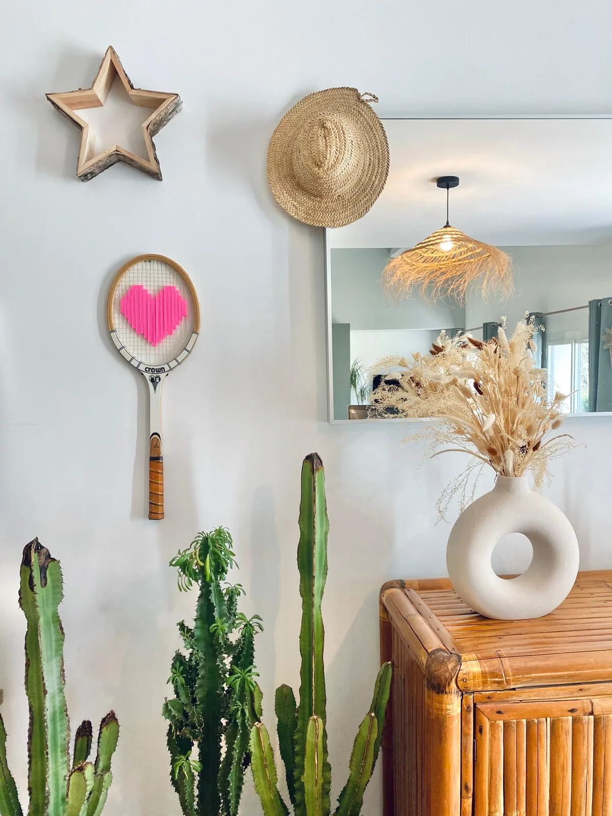 La raquette au cœur rose brodé accrochée dans une entrée lumineuse, avec une étoile, un cactus et un vase