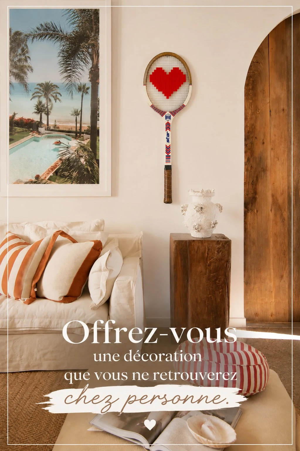 Raquette vintage au cœur rouge brodé dans un salon avec un canapé et une affiche de palmiers